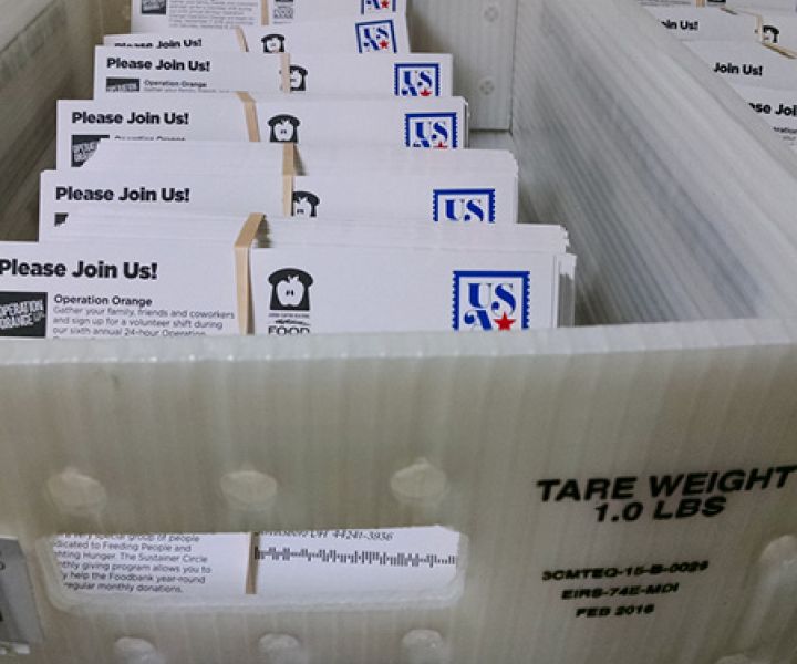 ray filled with neatly stacked envelopes stamped with 'USPS' and featuring the message 'Please Join Us!' for a community event, ready for mailing.