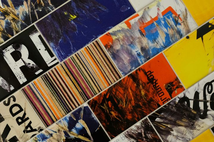 Abstract collage of mixed-media artwork featuring bold colours, textures, and patterns, including vibrant stripes, splashes of blue, yellow, and orange, and scattered text elements.