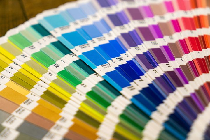 Close-up of a colourful Pantone swatch book, displaying a wide range of colour samples arranged in gradient order, from yellows and greens to blues and purples.